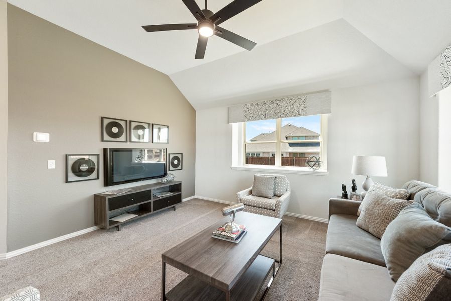 Living room with vaulted ceiling, ceiling fan, gray sofa, TV console, and carpet flooring