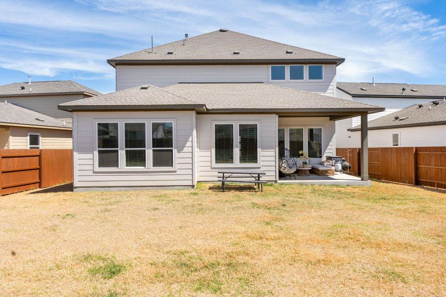 Rear view of property featuring a patio, a lawn, a fenced backyard, and a shingled roof