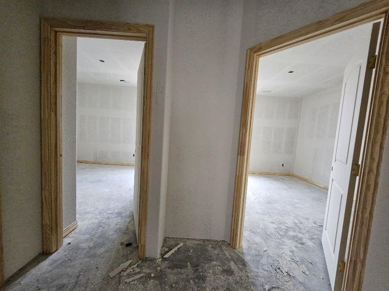 Unfinished interior spaces featuring raw concrete flooring, exposed drywall, and light wood door frames Unfinished interior spaces featuring raw concrete flooring, exposed drywall, and light wood door frames