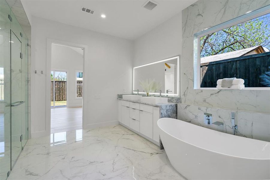Bathroom with a marble finish shower, visible vents, vanity, and a soaking tub