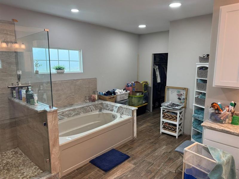 Full bath with a spacious closet, walk in shower, a garden tub, wood tiled floors, and recessed lighting Full bath with a spacious closet, walk in shower, a garden tub, wood tiled floors, and recessed lighting