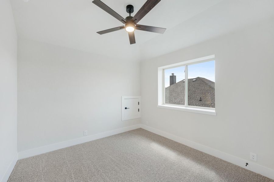 Empty bedroom with carpet flooring, ceiling fan, vaulted ceiling, and single window with natural light