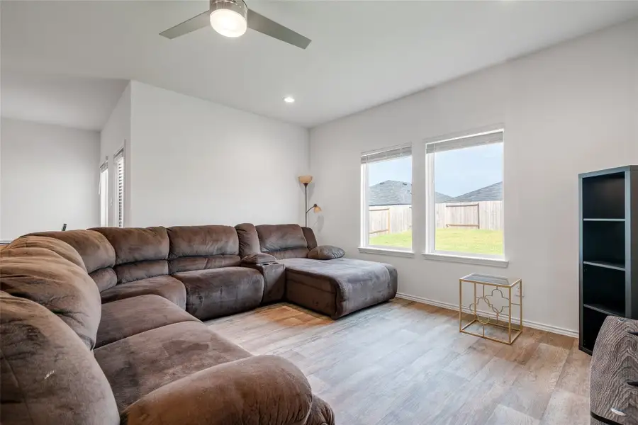 The living room features multiple windows with privacy blinds and a sleek ceiling fan, creating a comfortable and stylish space to relax. The living room features multiple windows with privacy blinds and a sleek ceiling fan, creating a comfortable and stylish space to relax.