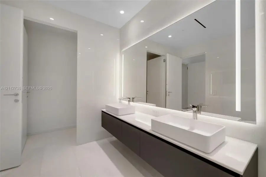 Floating dual-sink vanity featuring square vessel basins, quartz countertop, large wall-to-wall integrated LED vanity mirror, and polished chrome fixtures