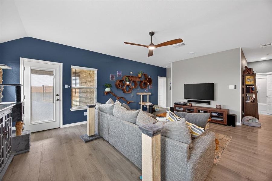 Living area with a ceiling fan, wood finished floors, and lofted ceiling
