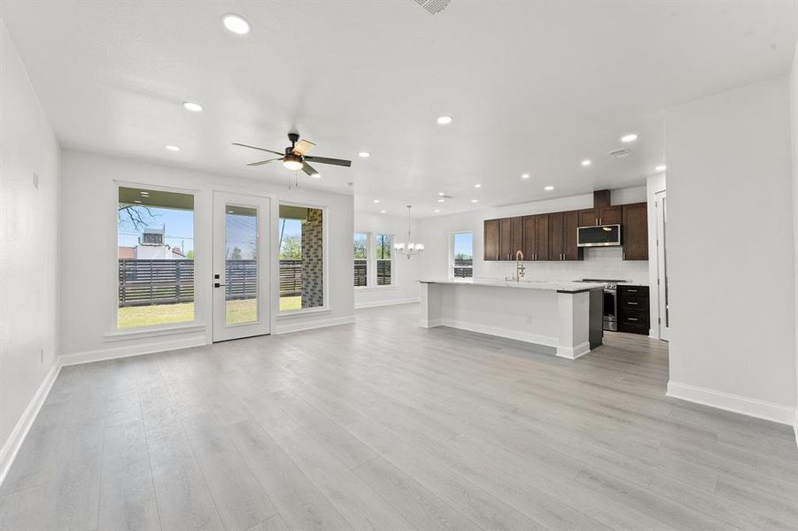 Unfurnished living room with suspended lighting, ceiling fan, and light wood-style flooring