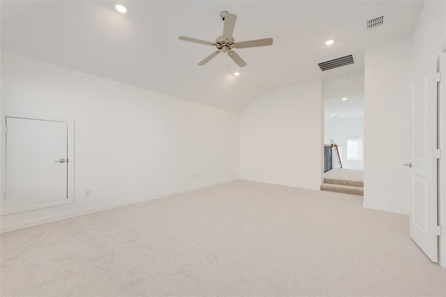 Spare room featuring ceiling fan, light colored carpet, and vaulted ceiling