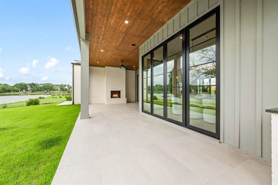 View of patio / terrace with a large fireplace, a water view, and a ceiling fan View of patio / terrace with a large fireplace, a water view, and a ceiling fan