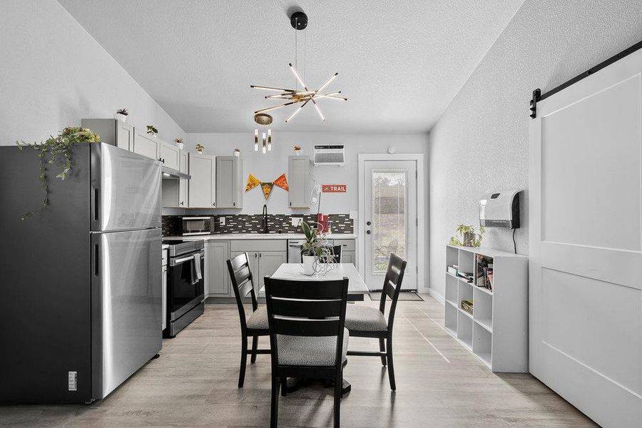 The sleek kitchen showcases brand-new stainless steel appliances, while large windows fill the home with natural light.