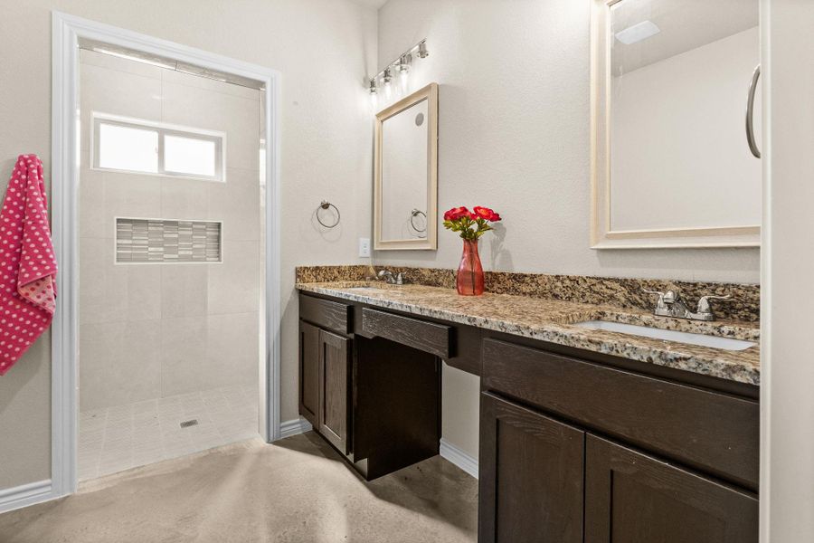 Full bath with double vanity and tiled shower