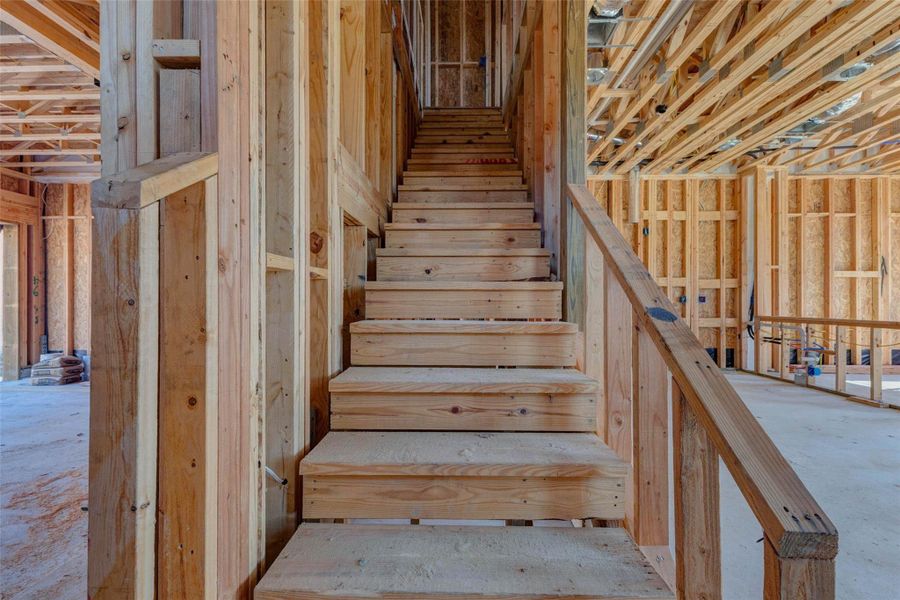 Staircase construction detail showing the framed stairway connecting the main level to the second floor. The exposed wood steps, rail framing, and surrounding structural elements highlight the home’s two-story layout and central circulation point, giving buyers a closer look at the craftsmanship and progress taking shape inside. Staircase construction detail showing the framed stairway connecting the main level to the second floor. The exposed wood steps, rail framing, and surrounding structural elements highlight the home’s two-story layout and central circulation point, giving buyers a closer look at the craftsmanship and progress taking shape inside.