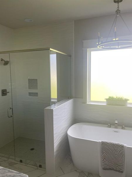 Full bathroom featuring a shower stall, a soaking tub, marble look tiles, and a chandelier Full bathroom featuring a shower stall, a soaking tub, marble look tiles, and a chandelier