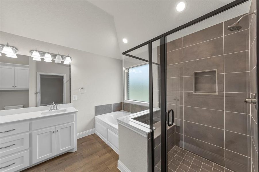 Bathroom featuring a glass-enclosed shower with tiled walls and floor, a built-in shower niche, and a bathtub with a privacy window