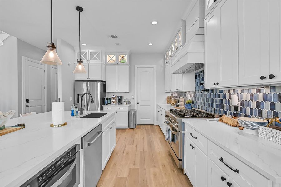 Quartz countertops, under cabinet lighting, pot filler, designer backsplash details give this kitchen a refined coastal look. Every finish was selected with style and practicality in mind.