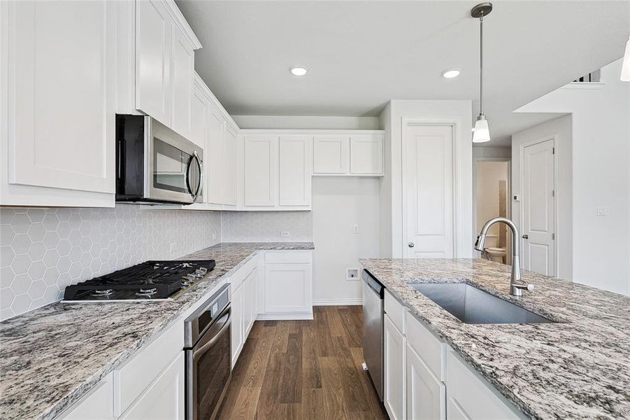 Kitchen featuring sink, white cabinetry, backsplash, and stainless steel appliances