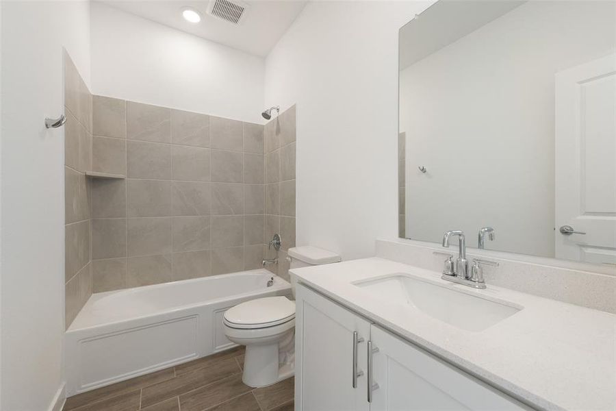 Full bathroom with vanity, tiled shower / bath combo, and toilet