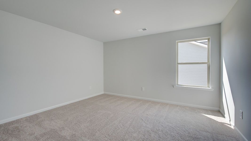 McKinley II generously sized secondary bedroom with carpet flooring and natural light at Brighton in Locust Grove, GA.