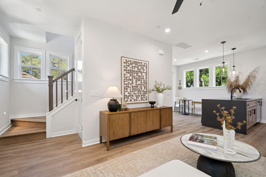 Luminous open-concept living space features warm LVP flooring and a modern kitchen island with pendant lighting. Luminous open-concept living space features warm LVP flooring and a modern kitchen island with pendant lighting.