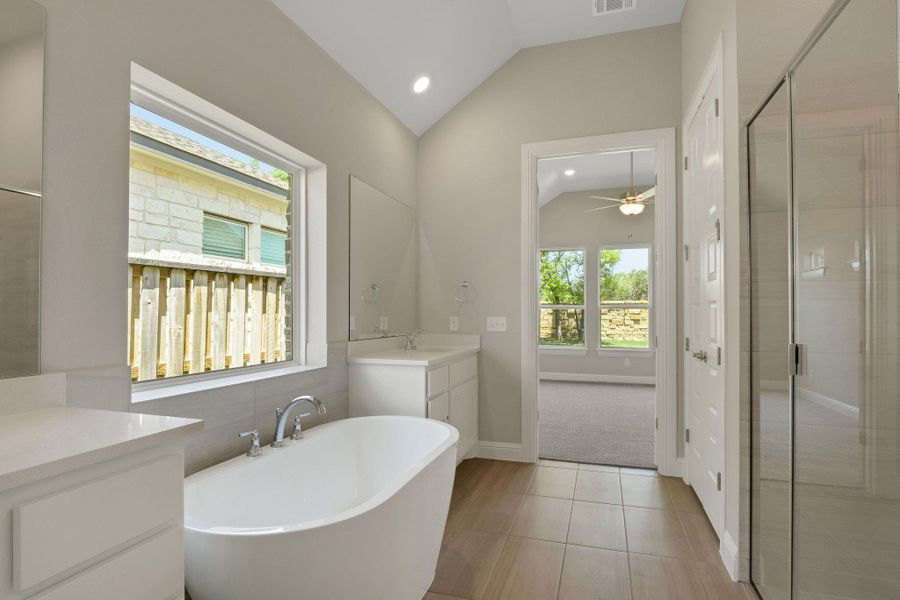 Full bathroom featuring a shower stall, a freestanding tub, vanity, and lofted ceiling