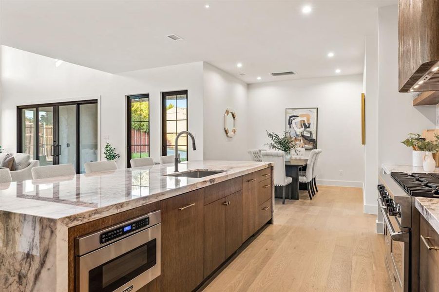 Kitchen with light stone counters, appliances with stainless steel finishes, light wood-style floors, recessed lighting, and modern cabinets Kitchen with light stone counters, appliances with stainless steel finishes, light wood-style floors, recessed lighting, and modern cabinets