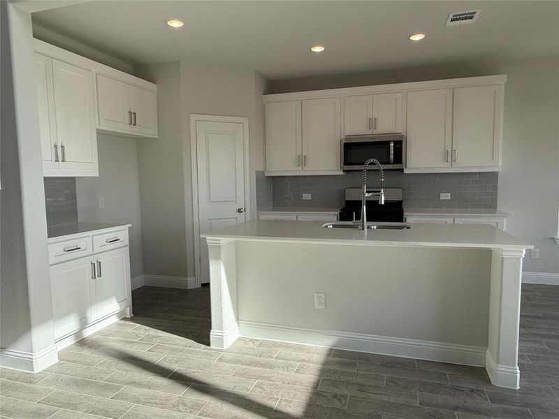 Kitchen with a center island with sink, white cabinetry, dark hardwood / wood-style floors, and sink