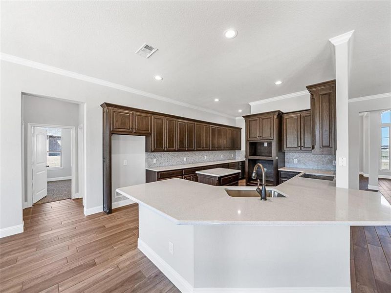 Prior listing photo. Property remains accurate - Kitchen featuring plenty of natural light, ornamental molding, light wood-style floors, tasteful backsplash, and recessed lighting