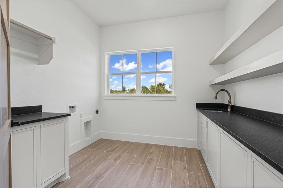Washroom with wood finish floors, washer hookup, cabinet space, and electric dryer hookup Washroom with wood finish floors, washer hookup, cabinet space, and electric dryer hookup