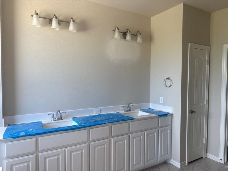 Dual vanity with white shaker-style cabinetry, integrated sinks, and chrome faucets Dual vanity with white shaker-style cabinetry, integrated sinks, and chrome faucets
