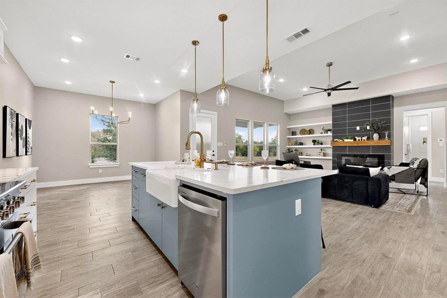 Kitchen featuring decorative light fixtures, dishwasher, light stone countertops, a kitchen island with sink, and open floor plan