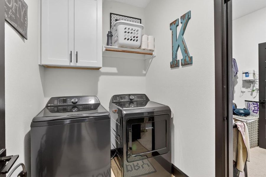 Laundry area featuring white cabinetry, a floating wood-finish shelf, and neutral wall finishes