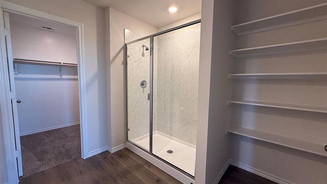 Walk-in shower with clear glass enclosure and textured wall surround