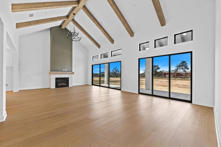 Unfurnished living room featuring a glass covered fireplace, light wood-style flooring, and suspended lighting