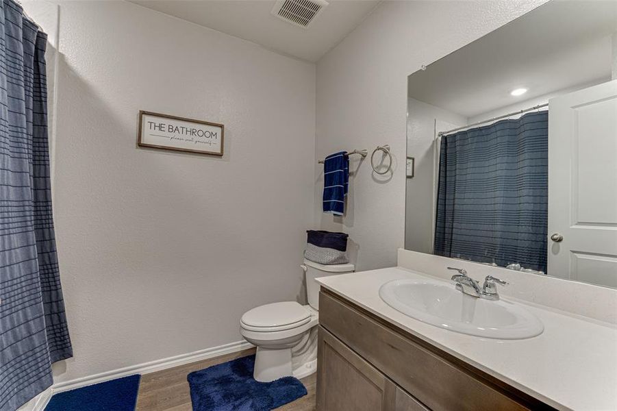 Bathroom with a shower with shower curtain, vanity, toilet, and wood-type flooring