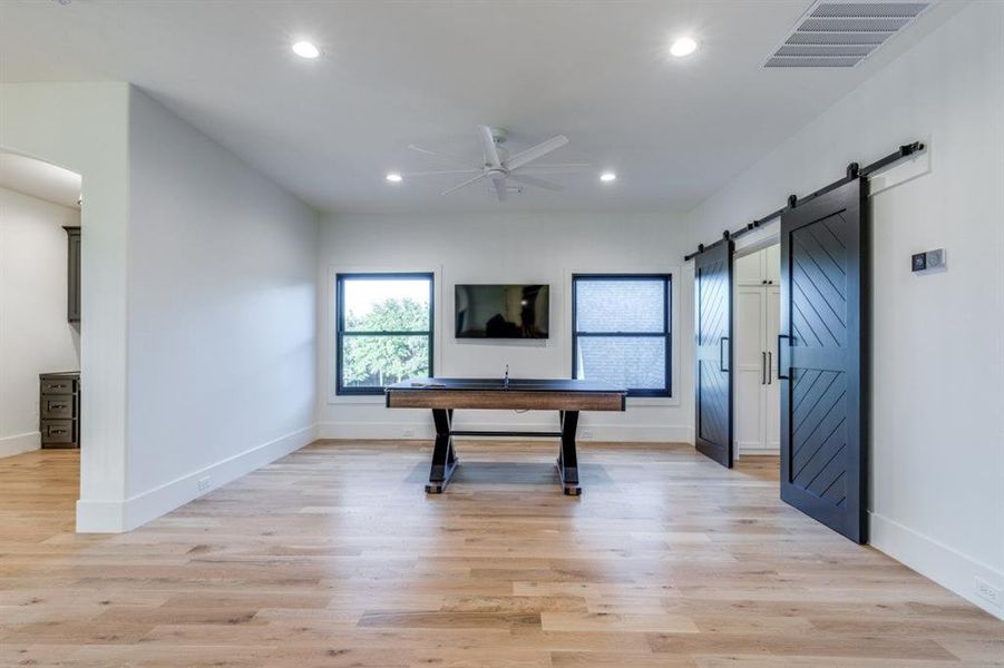 Unfurnished living room featuring light wood-type flooring, a ceiling fan, recessed lighting, a barn door, and arched walkways Unfurnished living room featuring light wood-type flooring, a ceiling fan, recessed lighting, a barn door, and arched walkways