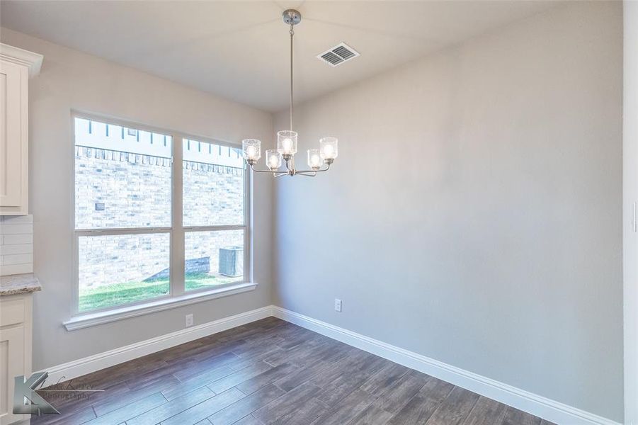 Unfurnished dining area featuring dark wood finish ceramic tile flooring and a chandelier