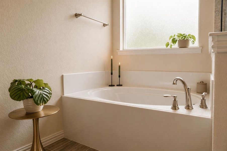 Built-in soaking tub with brushed nickel fixtures and a frosted privacy window