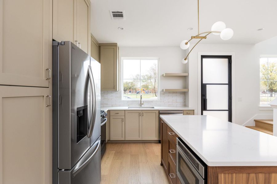 Kitchen featuring stainless steel appliances, a kitchen island, light wood-type flooring, open shelves, and cream cabinets