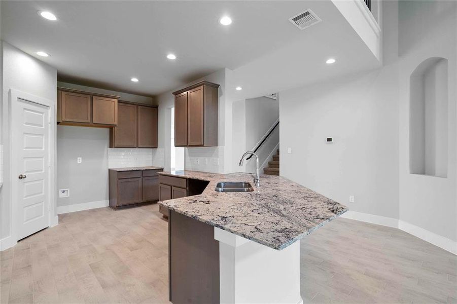 This stunning kitchen displays such beautiful cabinets, custom neutral paint, granite countertops, light modern backsplash, and SS appliances, oversized kitchen with extra storage, breakfast bar, recessed lighting, high ceilings and pantry.