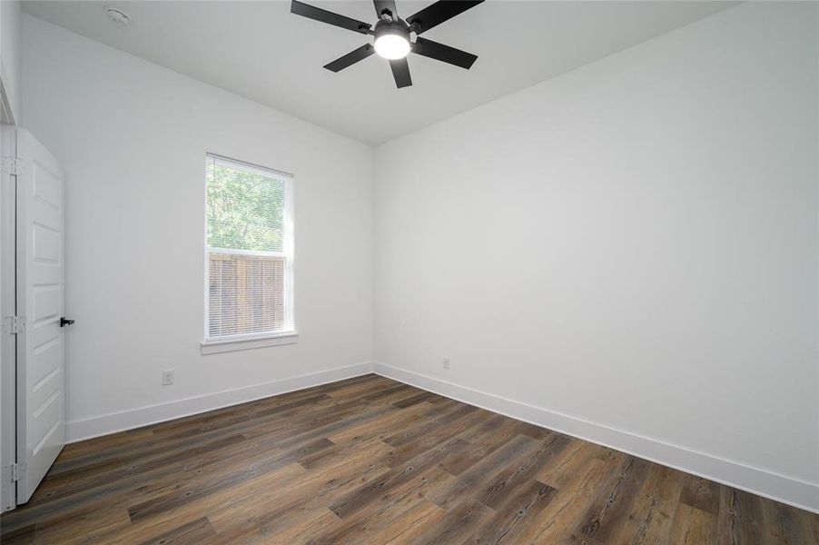 Spare room with dark wood-type flooring and ceiling fan