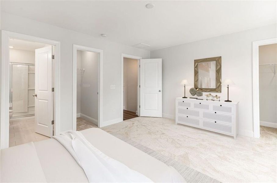 Bedroom featuring a closet, connected bathroom, a spacious closet, and light hardwood / wood-style flooring