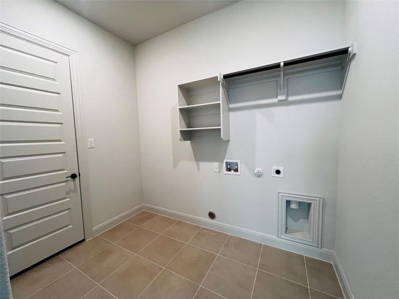 Laundry area with hookup for a gas dryer, hookup for a washing machine, electric dryer hookup, and light tile patterned flooring