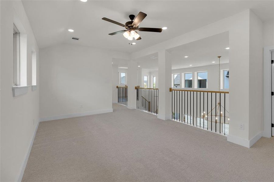 Spacious carpeted loft with an angled ceiling, recessed lighting, and a ceiling fan