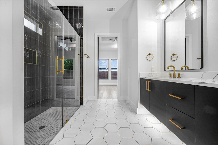 Bathroom featuring a vanity, patterned tile flooring, abundant natural light, and a tiled shower. Bathroom featuring a vanity, patterned tile flooring, abundant natural light, and a tiled shower.