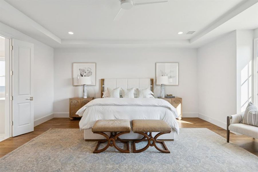 Bedroom with wood finished floors, a ceiling fan, recessed lighting, and a tray ceiling Bedroom with wood finished floors, a ceiling fan, recessed lighting, and a tray ceiling