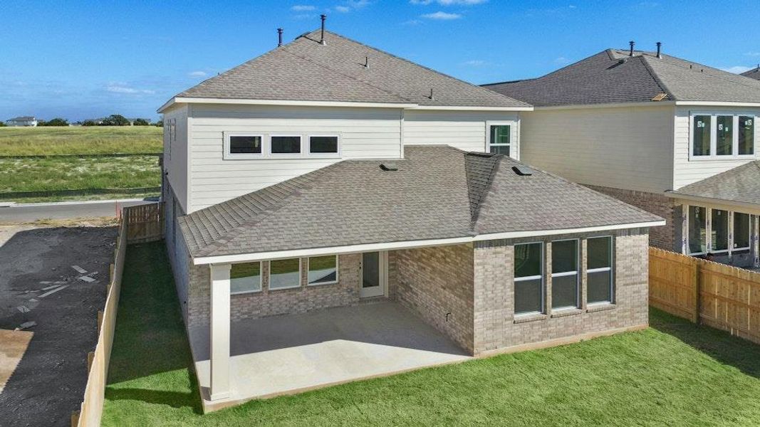 Rear view of property featuring a shingled roof, a patio, and brick siding