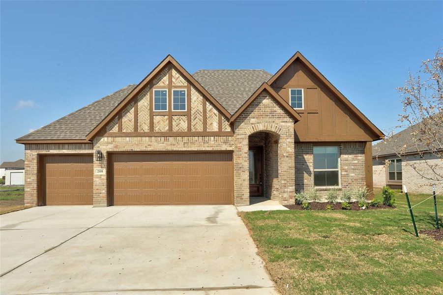Tudor home with brick siding, concrete driveway, a shingled roof, a front yard, and board and batten siding Tudor home with brick siding, concrete driveway, a shingled roof, a front yard, and board and batten siding