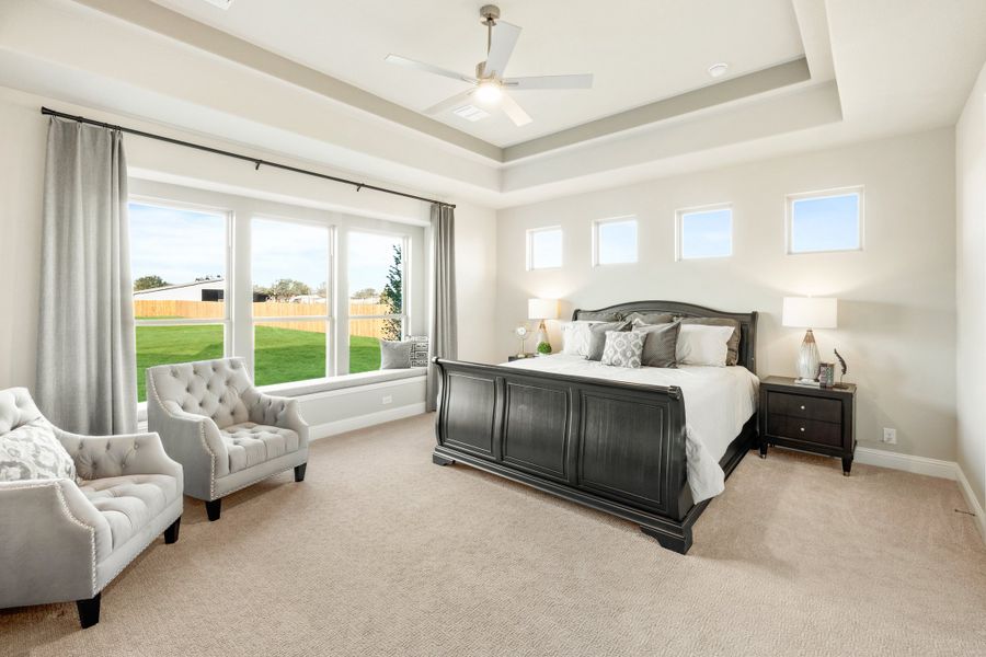 Master bedroom with tray ceiling, ceiling fan, dark wood sleigh bed, and large windows with backyard view Master bedroom with tray ceiling, ceiling fan, dark wood sleigh bed, and large windows with backyard view