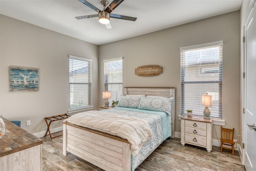 Bedroom with multiple windows, wood tiled floors, and ceiling fan