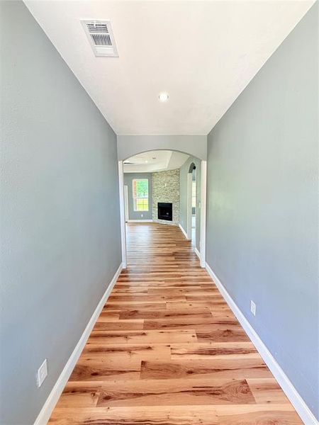 Hallway featuring wood-finish flooring, light blue walls, and white baseboards