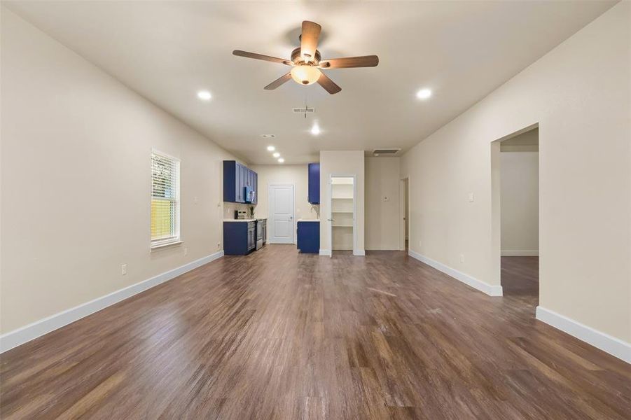 Unfurnished living room featuring ceiling fan and dark hardwood / wood-style floors